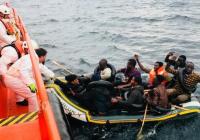 Individuals in a boat being intercepted at sea.