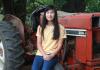 Prize winner Alysa Meng sitting in front of a red tractor and smiling.